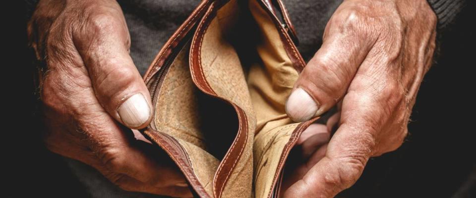 Empty wallet in the hands of an elderly man. Poverty in retirement concept