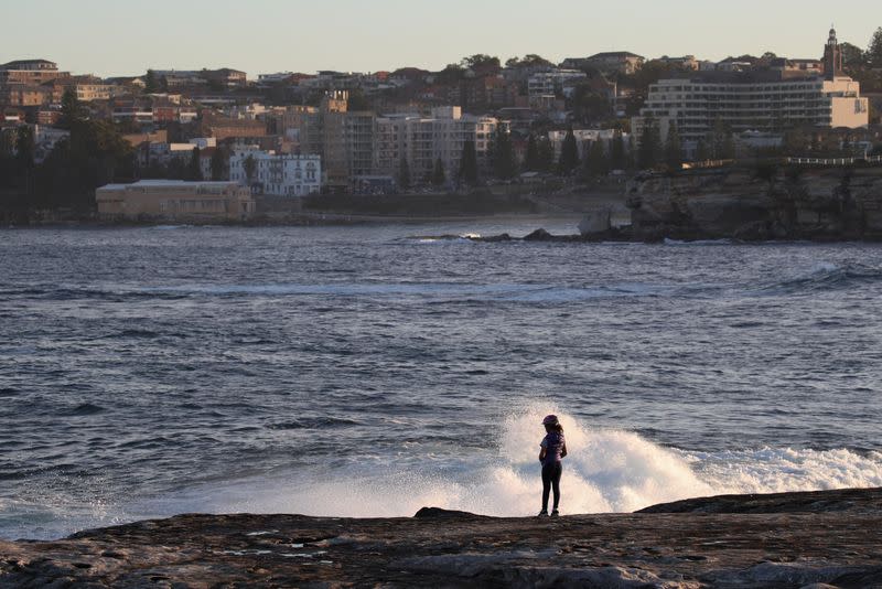 A child stands atop a cliff over the ocean in Sydney