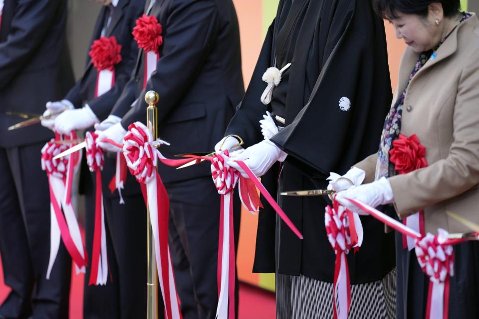 Guests attend the ribbon cutting during the opening ceremony of "Toyosu Senkyaku Banrai," an Edo Period-themed hot spring complex at Toyosu Fish Market Thursday, Feb. 1, Tokyo. Japan's biggest fish market on Thursday opened a long-awaited outer section with Japanese-style seafood restaurants and a spa for relaxation, as the wholesale venue that has struggled since relocating from the beloved Tsukiji market seeks to lure more visitors. (AP Photo/Eugene Hoshiko)