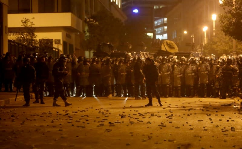 Stones are seen on the ground as Lebanese police gather during a protest against the newly formed government in Beirut