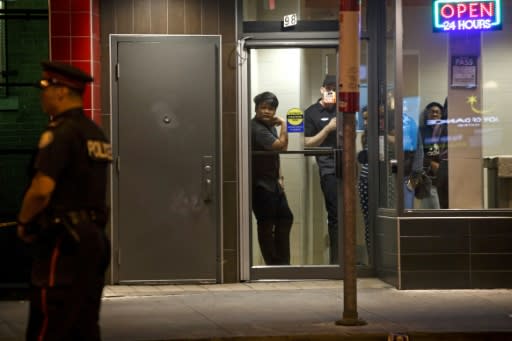 People look out the window from a restaurant as Toronto Police officers stand watch at the scene of the shooting in Toronto's Greektown
