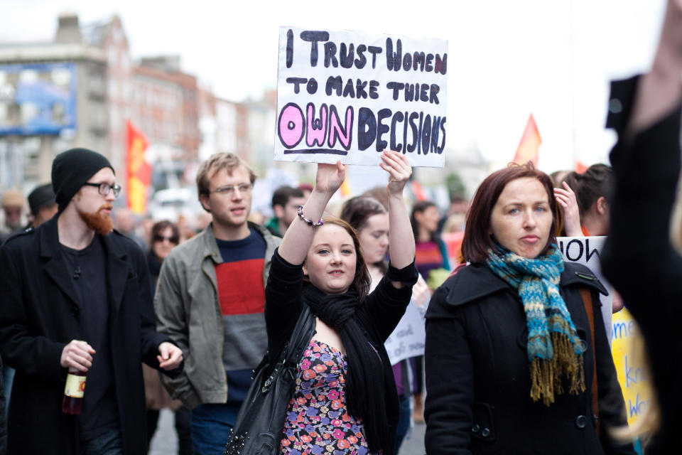 A woman holding up a sign at a protest for abortion rights that reads, "I trust women to make their own decisions."