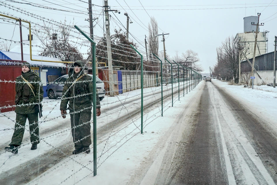 Russian border guards seen behind barbed wire, patrol an area along the Russian side of the Ukraine - Russia border in Milove town, eastern Ukraine, Sunday, Dec. 2, 2018. On a map, Chertkovo and Milove are one village, crossed by Friendship of Peoples Street which got its name under the Soviet Union, and on the streets in both places, people speak a mix of Russian and Ukrainian without turning choice of language into a political statement. (AP Photo/Evgeniy Maloletka)