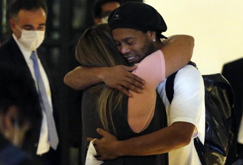 Former Brazilian soccer star Ronaldinho is embraced by a woman as he arrives at a hotel where he is to stay under house arrest in Asuncion, Paraguay, Tuesday, April 7, 2020. Ronaldinho and his brother Roberto De Assis Moreira spent a month in jail accused of entering Paraguay with fake passports. (AP Photo/Jorge Saenz)