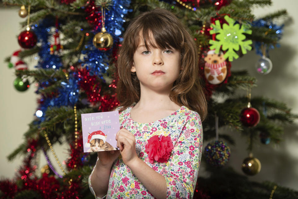 Florence Widdicombe, 6, poses with a Tesco Christmas card from the same pack as a card she found containing a message from a Chinese prisoner, in London, Sunday, Dec. 22, 2019. The U.K.-based grocery chain Tesco has halted production at a factory in China after a British newspaper said it used forced labor to produce charity Christmas cards. Tesco said Sunday it had stopped production and launched an investigation after the Sunday Times newspaper raised questions about the factory's labor practices. (Dominic Lipinski/PA via AP)