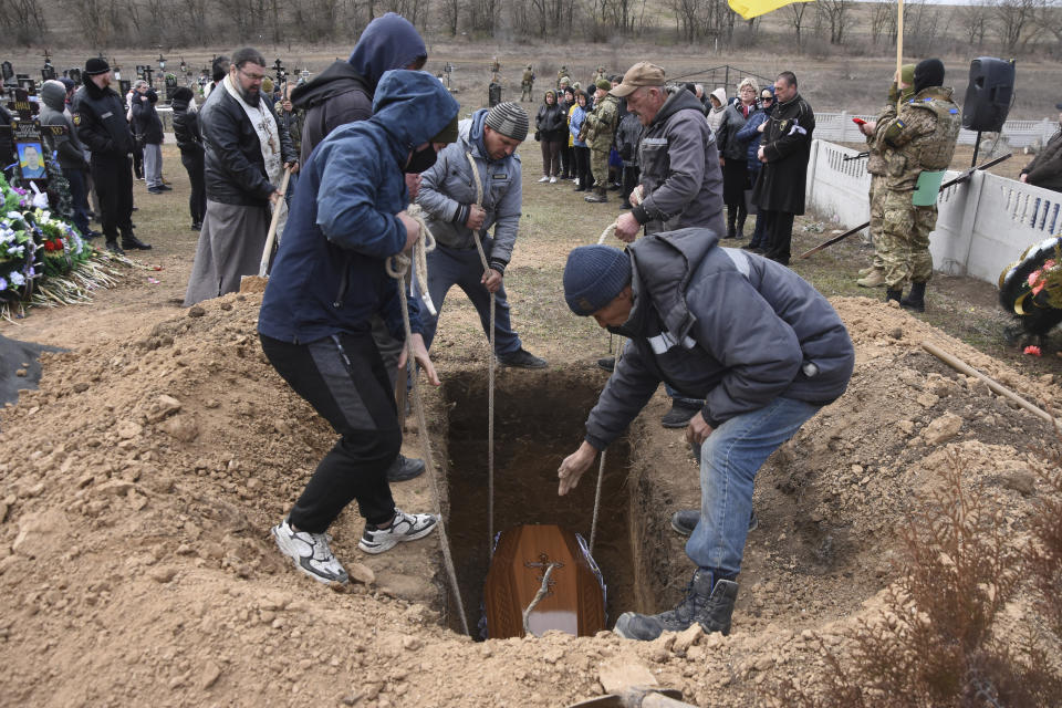 Men lower the coffin of Ukrainian serviceman Oleksiy Lunyov into his gravesite in Yuzhne, Odessa region, Ukraine, Sunday, March 27, 2022. Lunyov was killed during a Russian missile attack in Mykolaiv on March 18. (AP Photo/Max Pshybyshevsky)