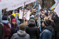 Demonstrators, one holding a poster reading "Vaccination kills" as they gather to protest against COVID-19 restrictions and vaccine mandates in Kyiv, Ukraine, Wednesday, Nov. 3, 2021. In a bid to stem contagion, Ukrainian authorities have required teachers, government employees and other workers to get fully vaccinated by Nov. 8 or face having their salary payments suspended. In addition, proof of vaccination or a negative test is now required to board planes, trains and long-distance buses. (AP Photo/Efrem Lukatsky)