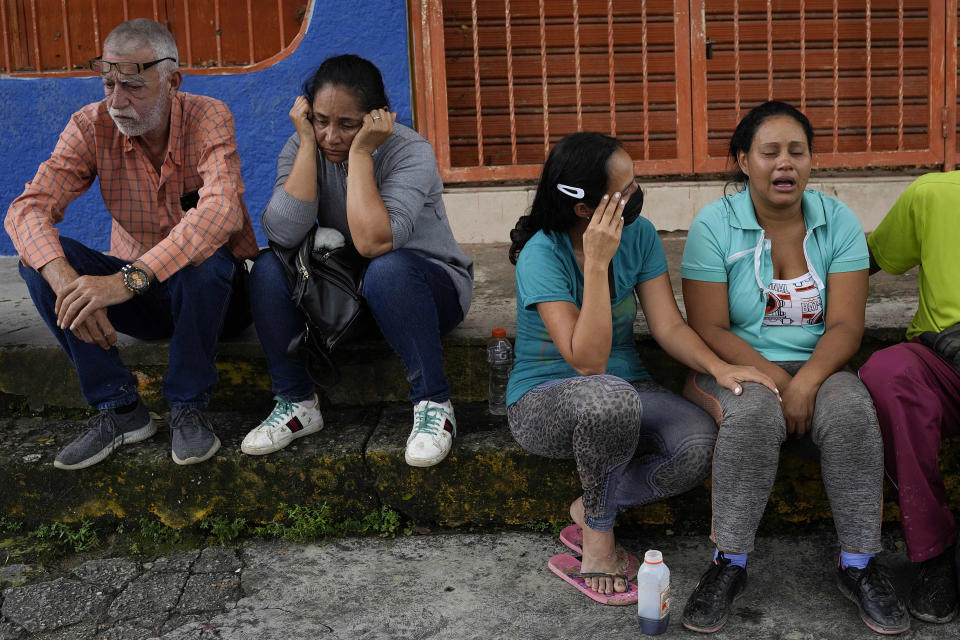 Residents sit outside a health center waiting for news from missing relatives after flooding in Las Tejerias, Venezuela, Sunday, Oct. 9, 2022. At least two people died after days of heavy rain caused flash flooding and the overflow of a ravine. (AP Photo/Matias Delacroix)