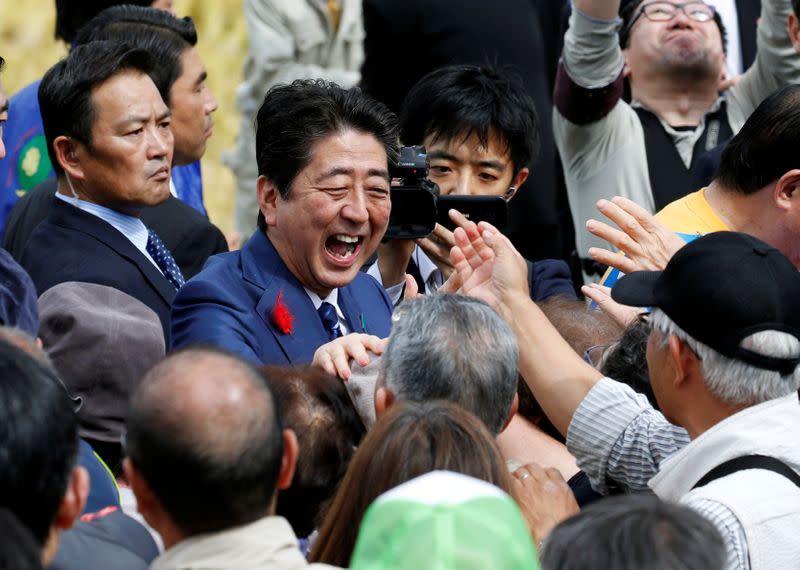 FILE PHOTO: Japan's Prime Minister Shinzo Abe, who is also ruling Liberal Democratic Party leader, shakes hands with his supporters after an election campaign rally in Fukushima