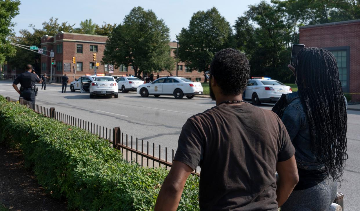 Bystanders look on after police shot 33-year-old Orlando Mitchell near the intersection of East 10th and North Delaware streets Friday, Sept. 16, 2022, in Indianapolis. Mitchell is expected to survive.