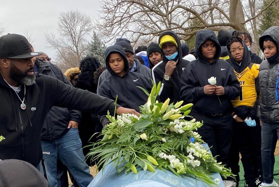 Indy Steelers coach Darryl Smith Sr. reaches for a flower from the casket of Richard Donnell Hamilton as team members look on. Smith helped Hamilton coach the youth football league.