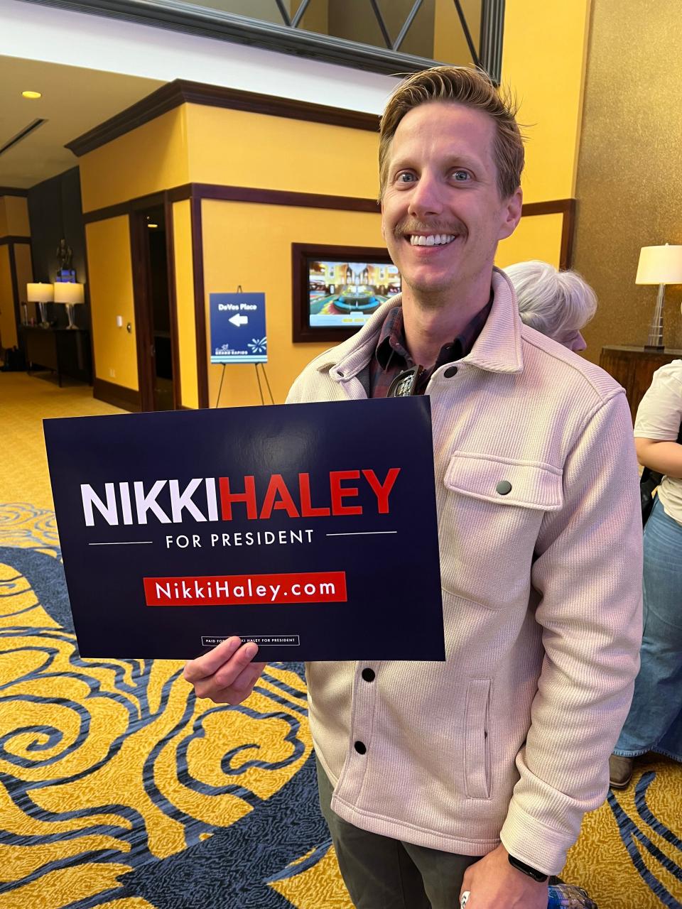 Scott Muellerleile, 37, poses with a sign supporting Nikki Haley for president before her event at the Amway Grand Plaza on Monday, Feb. 26, 2024, in Grand Rapids, Mich. Muellerleile, of Grand Haven, said he supports Haley because she represents a more "middle of the road" option than President Joe Biden and former President Donald Trump, and hopes she runs as a third-party candidate.