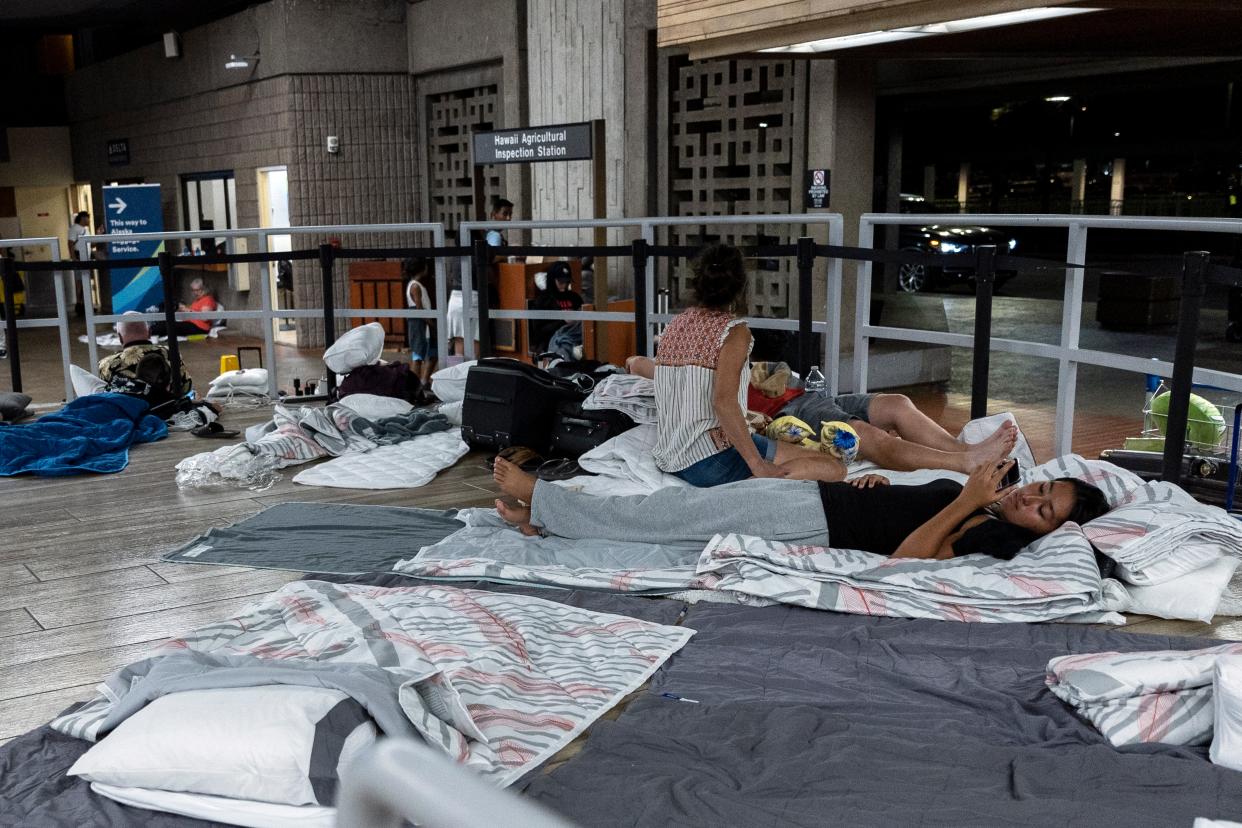 Tourists who were evacuated following wild fire destruction settle for the night as they wait for a flight out of Kahului Airport (EPA)