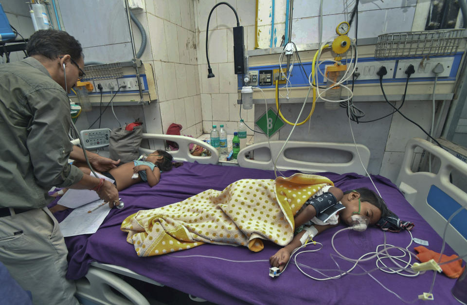 In this Tuesday, June 18, 2019 photograph, a doctor attends to children showing symptoms of acute encephalitis syndrome at Sri Krishna Medical College Hospital in Muzaffarpur, Bihar state, India. More than 100 children have died in an encephalitis outbreak in India's eastern state of Bihar, authorities said Tuesday. (AP Photo/Aftab Alam Siddiqui)