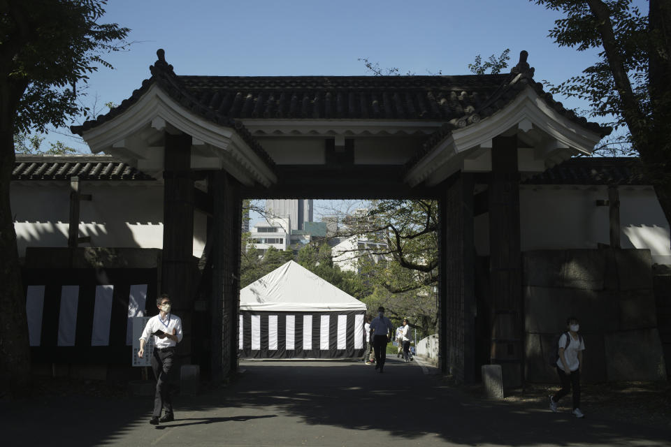 People go through a gate as they walk towards the building to be used for the state funeral of former Prime Minister Shinzo Abe as authorities have deployed extra officers to beef up securities in Tokyo, Monday, Sept. 26, 2022. Japanese Prime Minister Fumio Kishida is hosting the controversial state-sponsored ceremony for the former leader Tuesday. (AP Photo/Hiro Komae)