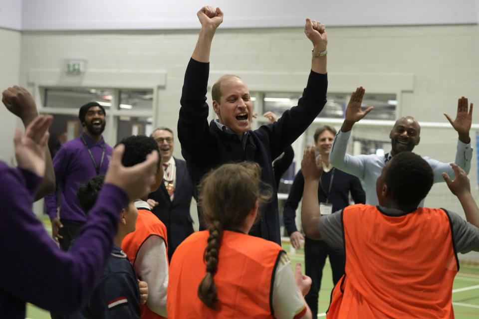 William smiling and raising his arms in a cheer among a group of people