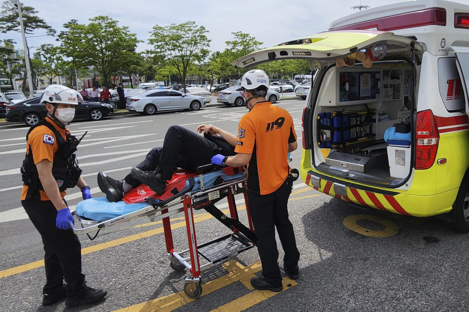 Rescue workers move a passenger on a stretcher to an ambulance at Daegu International Airport in Daegu, South Korea, Friday, May 26, 2023. A passenger opened a door on an Asiana Airlines flight that later landing safely at a South Korean airport Friday, airline and government officials said. (Daegu Fire Station/Newsis via AP)