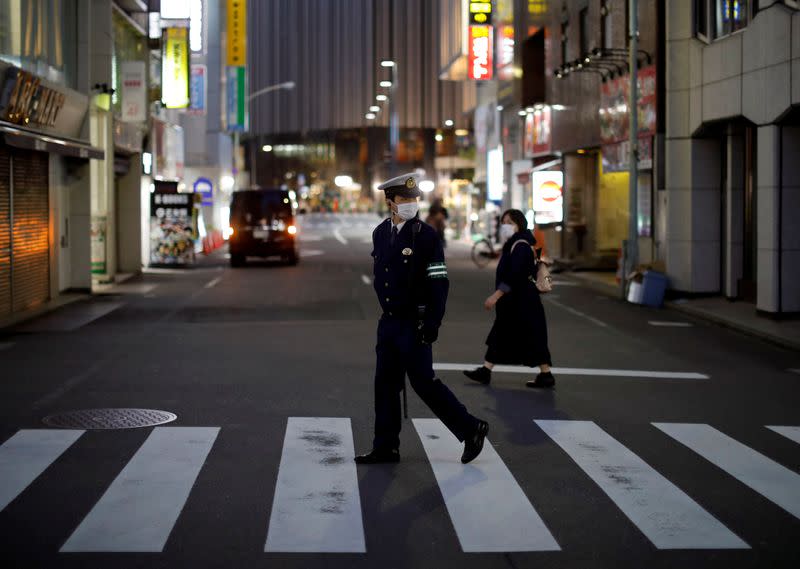 A police officer wearing a protective face mask patrols on the street following the coronavirus disease outbreak in Tokyo