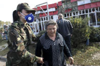 An Azerbaijani officer helps an elderly woman to leave a dangerous area after multiple rocket system shelling by Armenian forces in Barda, Azerbaijan, Wednesday, Oct. 28, 2020. The Azerbaijani Defense Ministry rejected all the accusations and in turn accused Armenian forces of using the Smerch multiple rocket system to fire at the Azerbaijani towns of Terter and Barda. The strike on Barda killed more than 20 people and wounded 60, Azerbaijani officials said. (AP Photo/Aziz Karimov)