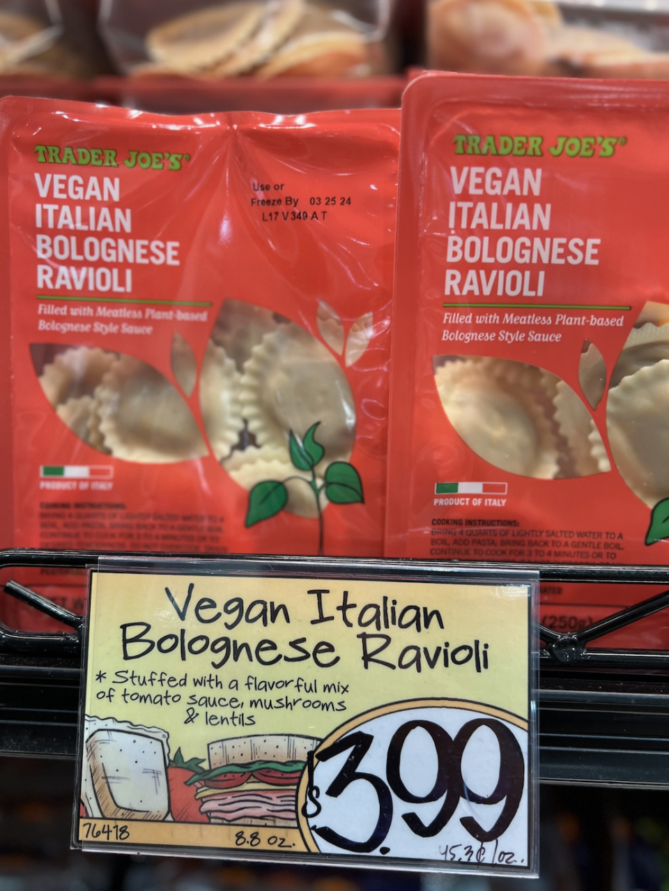 Packages of Trader Joe's Vegan Italian Bolognese Ravioli on a shelf with a price tag of $3.99 below