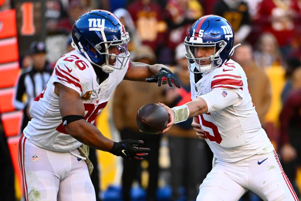 New York Giants quarterback Tommy DeVito hands off to running back Saquon Barkley against the Washington Commanders during the second half at FedExField.