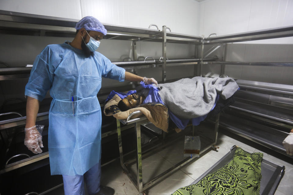 A morgue worker checks the body of a Palestinian killed in the Israeli bombardment of the Gaza Strip in a morgue of the European Gaza Hospital in Khan Younis, Tuesday, Jan. 16, 2024. (AP Photo/Hatem Ali)