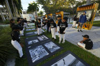 Kids from the Marlins Nike RBI youth sports program look at images of late Major League Baseball player Roberto Clemente during the installation of a traveling exhibit titled "3000," in a nod to Clemente's 3000 career hits, at Miami Marlins' loanDepot Park in Miami, Wednesday, Jan. 31, 2024. The tribute to the Pittsburgh Pirates outfielder will be on display at the park during baseball's Caribbean Series, which runs from Feb. 1 through Feb. 9. (AP Photo/Rebecca Blackwell)
