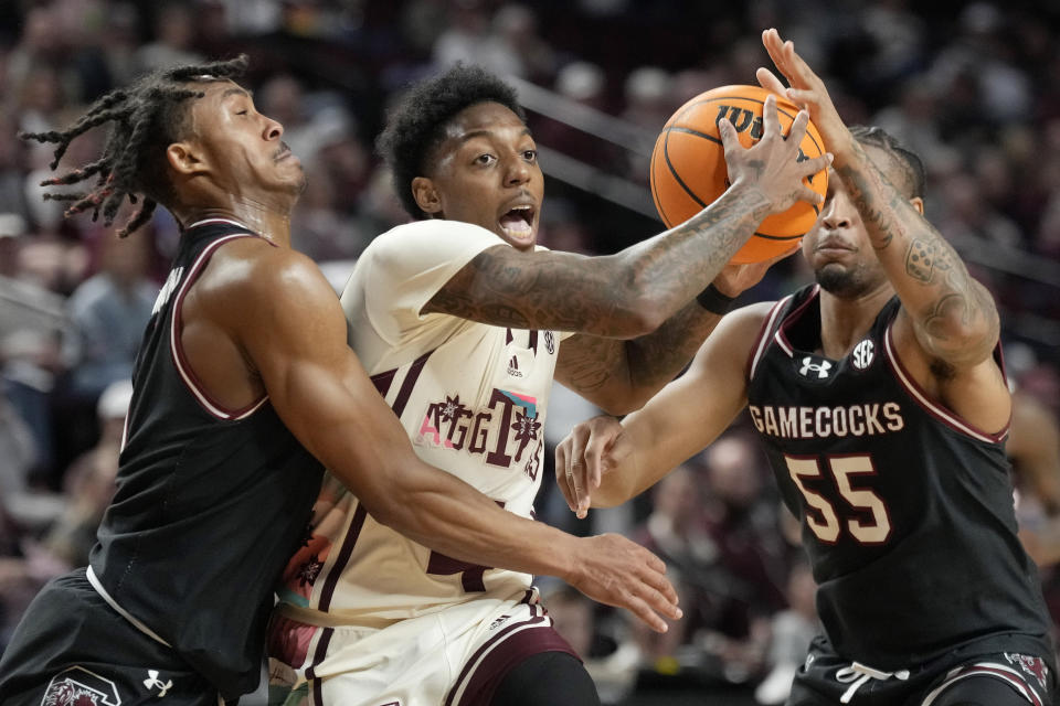 Texas A&M guard Wade Taylor IV (4) drives the lane against South Carolina guard's Meechie Johnson (5) and Ta'Lon Cooper (55) during the first half of an NCAA college basketball game Wednesday, Feb. 28, 2024, in College Station, Texas. (AP Photo/Sam Craft)