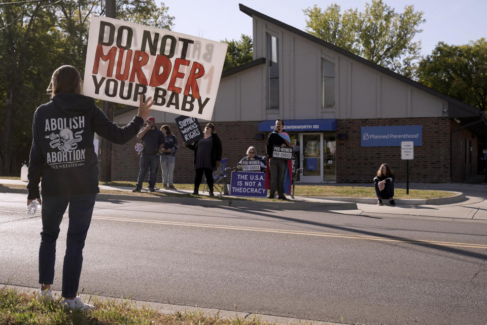 Demonstrators on both sides of the abortion issue stand outside a Planned Parenthood clinic Saturday, Oct. 15, 2022, in Kansas City, Kan. (AP Photo/Charlie Riedel)