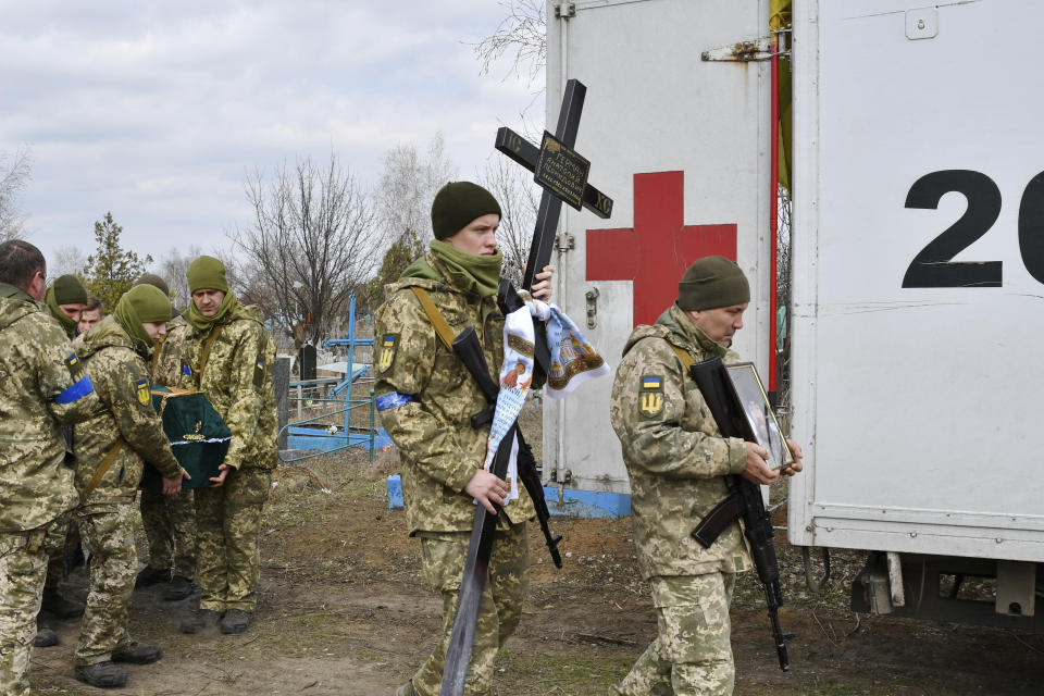 Ukrainian serviceman carry a coffin, left, of their comrade Anatoly German during a funeral ceremony in Kramatorsk, Ukraine, Tuesday, April 5, 2022. Anatoly German was killed during fightings between Russian and Ukrainian forces near the city of Severodonetsk. He leaves a wife, daughter Adelina, 9, son Kirill, 3. (AP Photo/Andriy Andriyenko)