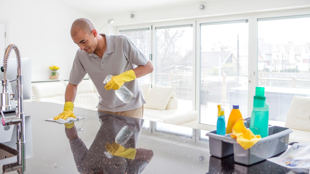 Shot of a young mixed race man cleaning a kitchen top.