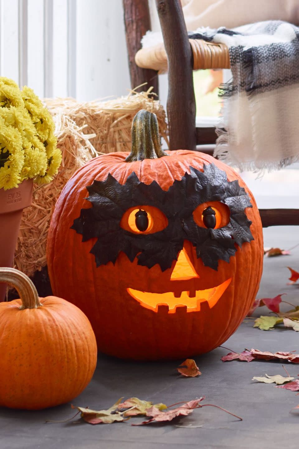 <p>Don't worry, this masked pumpkin won't steal your candy. His leaf mask is only there to help keep the mystery alive!<strong><br></strong></p><p><strong>Make the Masked Pumpkin:</strong> Paint eight real or artificial leaves with black spray paint; let dry. Layer leaves into a mask shape; hot-glue together. Cut eyeholes in mask. Trace eyeholes onto large orange pumpkin; carve. Glue black-painted acorns to straight pins, then push into eyeholes for pupils. Secure leaf mask to pumpkin with hot glue.</p>