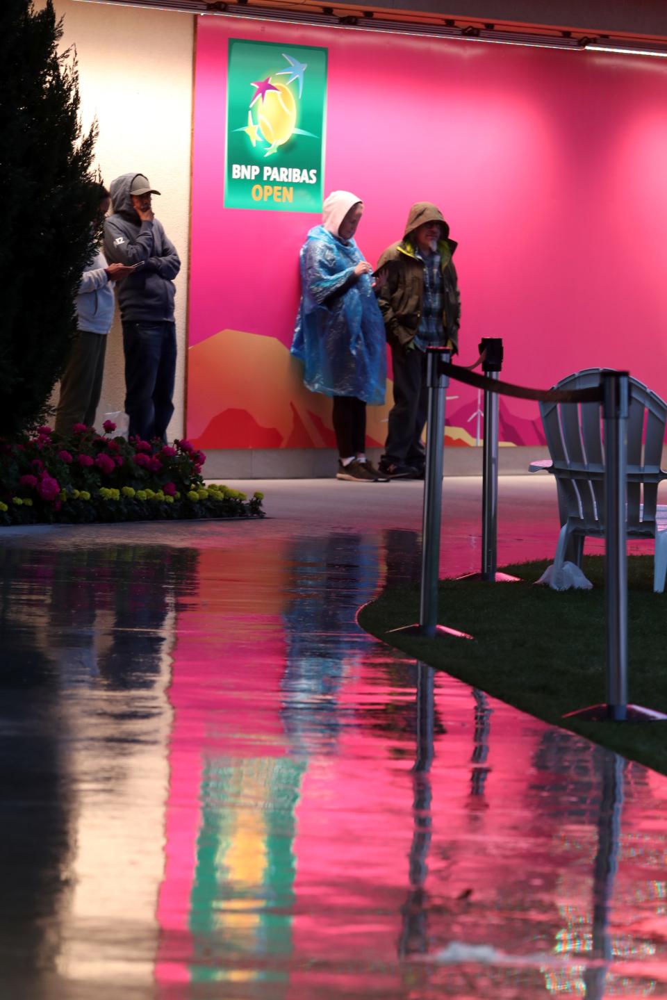 Tennis fans take cover from the rain which suspended play during the first round of the BNP Paribas Open in Indian Wells, Calif., on Wednesday, March 6, 2024.