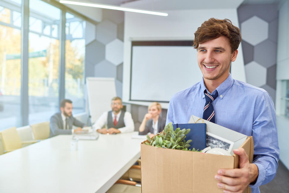 Portrait of smiling young man holding box of personal belongings being hired to work in business company, copy space