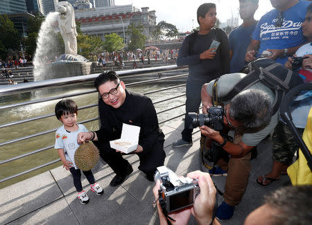 Howard, an Australian-Chinese impersonating North Korean leader Kim Jong Un, poses with a durian and a box of chicken rice at the Merlion Park in Singapore May 27, 2018. REUTERS/Edgar Su