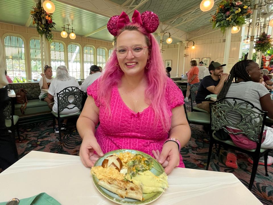 Author sitting at table at Crystal Palace with plate of food including bread, mac and cheese, cheese-covered broccoli, and mashed potatoes.