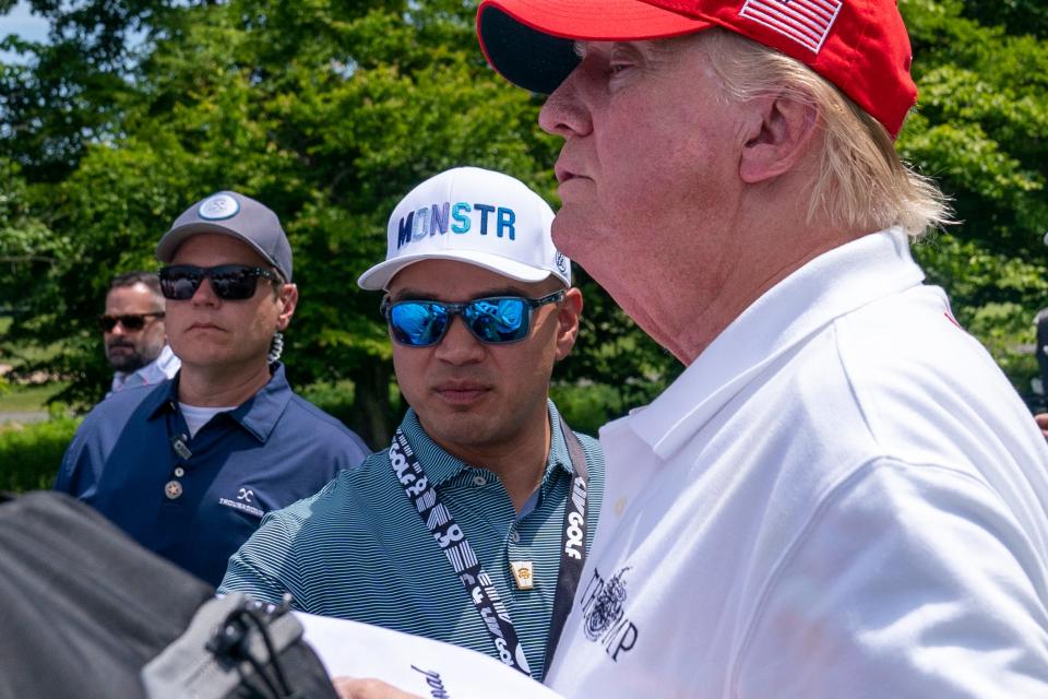 Walt Nauta, center, assists Former President Donald Trump as he greets supporters at the second round of the LIV Golf at Trump National Golf Club this past May.