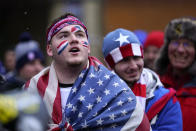 A man is draped in the United States flag as a group of U.S. men's national soccer team supporters march to Lower.com Field ahead of a FIFA World Cup qualifying soccer match against El Salvador, Thursday, Jan. 27, 2022, in Columbus, Ohio. (AP Photo/Julio Cortez)