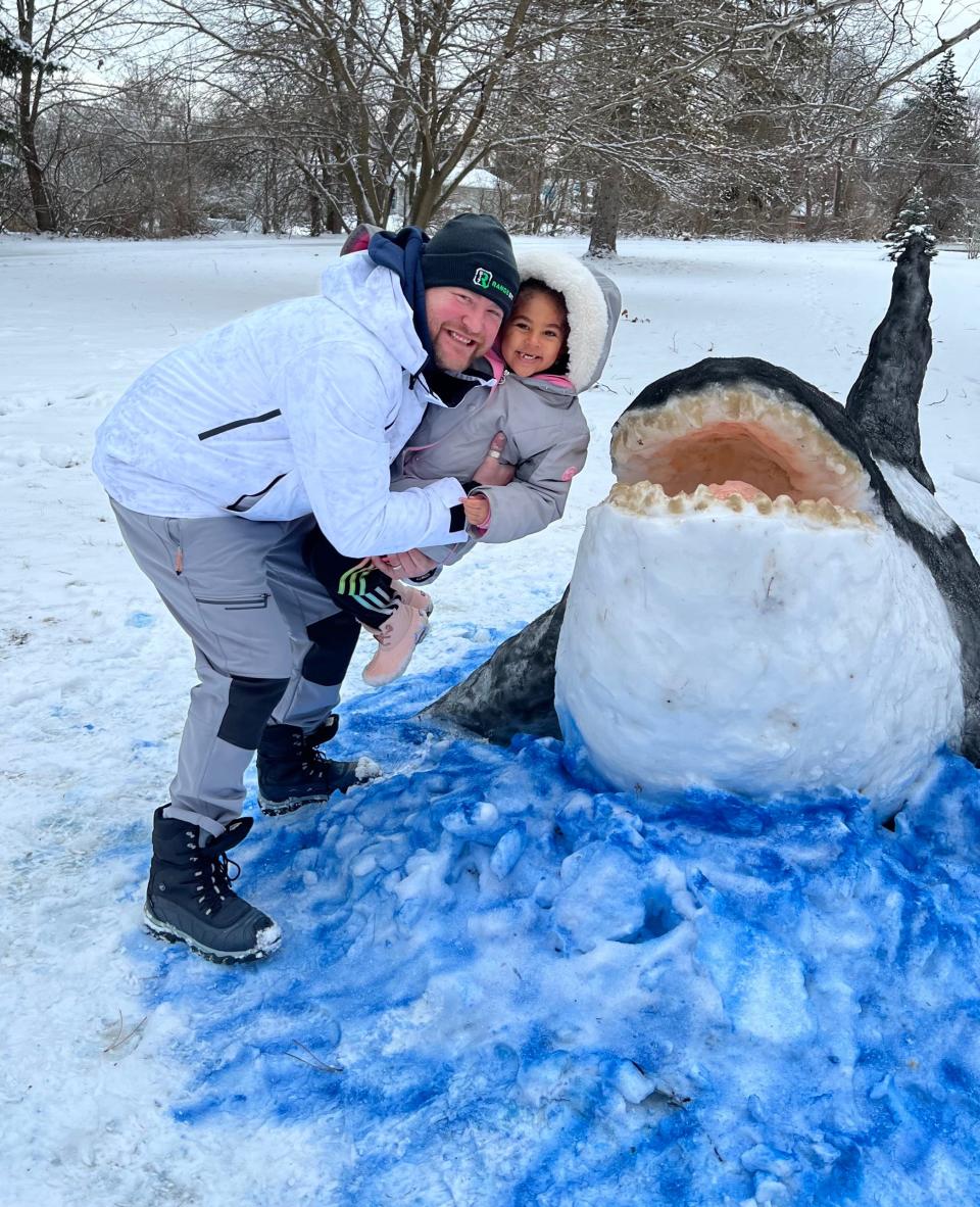 Jeffrey Kosloski poses with his orca sculpture and a girl who wanted to see his creation in Lansing, Michigan.