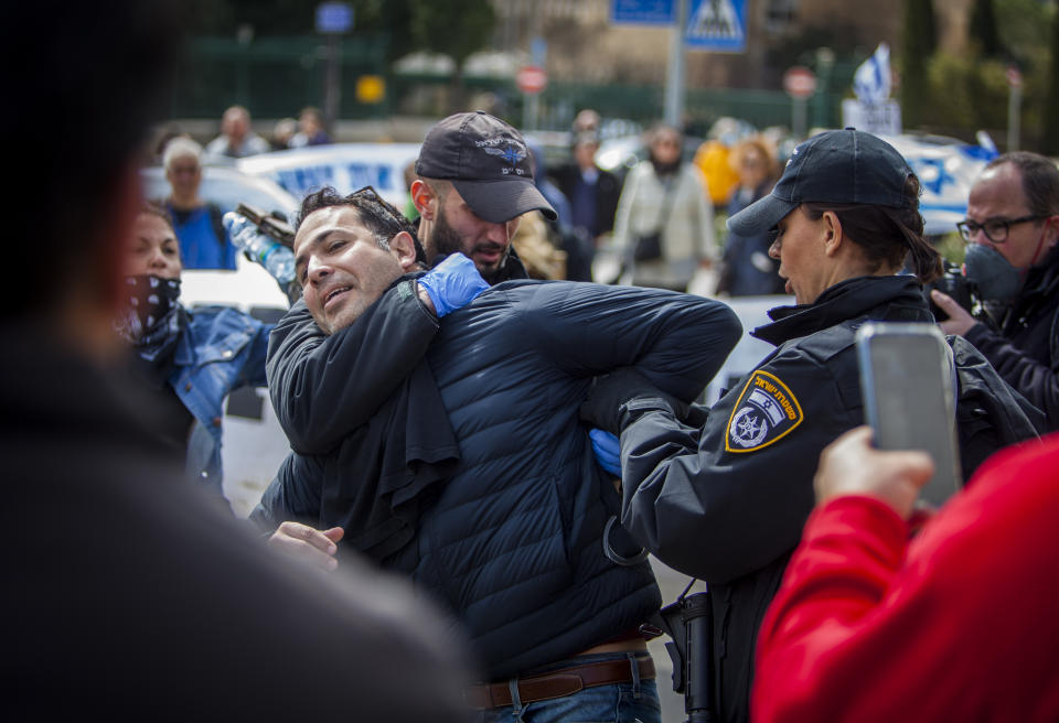 Israeli police officers arrest a man during a protest outside the Israeli parliament in Jerusalem, Thursday, March 19, 2020. Hundreds of people defied restrictions on large gatherings to protest outside parliament Thursday, while scores of others were blocked by police from reaching the area as they accused Prime Minister Benjamin Netanyahu's government of exploiting the coronavirus crisis to solidify his power and undermine Israel's democratic foundations. (AP Photo/Eyal Warshavsky)