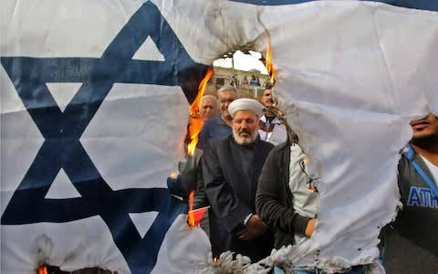 Protesters burn an Israeli flag during a demonstration, organised by Hizbollah, in the streets of the southern Lebanese port city of Sidon in December  - Credit: AFP