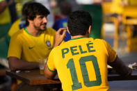 A fan wears a shirt in support of Pelé at a Brazilian fan party before the the World Cup round of 16 soccer match between Brazil and South Korea, in Doha, Dec. 5, 2022. The 82-year-old Pelé remained in a hospital in San Paulo recovering from a respiratory infection that was aggravated by COVID-19, but the news coming from Brazil early Monday was good. (AP Photo/Ashley Landis)