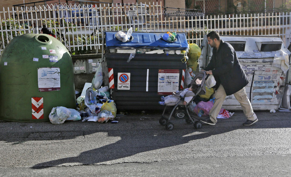 A man pushes a stroller in front of garbage bins rife with trash, in Rome, Wednesday, Nov. 7, 2018. Rome’s monumental problems of garbage and decay exist side-by-side with Eternal City’s glories. (AP Photo/Alessandra Tarantino)