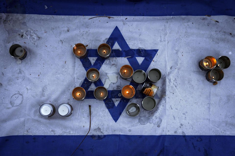 CAPTION CORRECTION: CORRECTS DEATH TOLL: Candles are placed on an Israeli flag at a vigil for the victims of the bloody Oct. 7 cross-border attack by Hamas militants, in which 1,200 people were killed and 240 people kidnapped, mostly Israeli citizens, in central Tel Aviv, Israel, Friday, Nov. 10, 2023. (AP Photo/Oded Balilty)