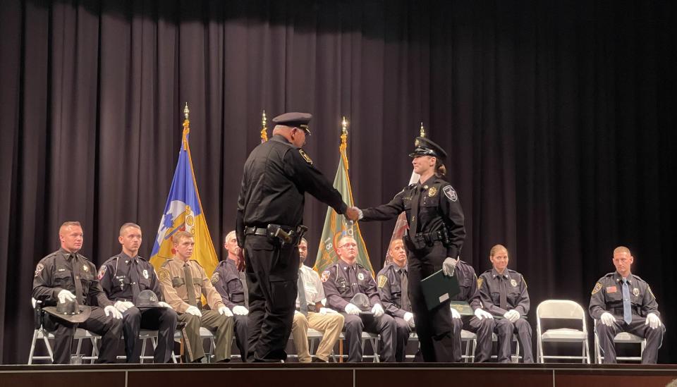 Chloe Shaulis, center right, accepts her certificate and a handshake from Indian Lake Borough Police Chief Jerry Bellak during the graduation ceremonies.