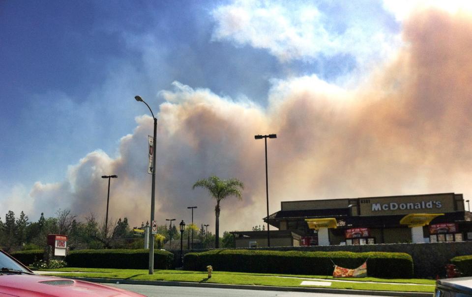 El humo de un incendio puede apreciarse en la población de Rancho Cucamonga, California, el miércoles 30 de abril de 2014. Casas y escuelas fueron evacuadas debido a que los vientos avivaron el fuego en las colinas de las montañas de San Bernardino en California. (Foto de AP/John Antczak)