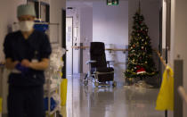 A Belgian Army medic works in the COVID-19 wing with a Christmas tree in the background at the St. Michiel Hospital in Brussels, Tuesday, Nov. 24, 2020. The Belgian military has been called into several hospitals and care homes to alleviate the stress on healthcare personnel. (AP Photo/Virginia Mayo)