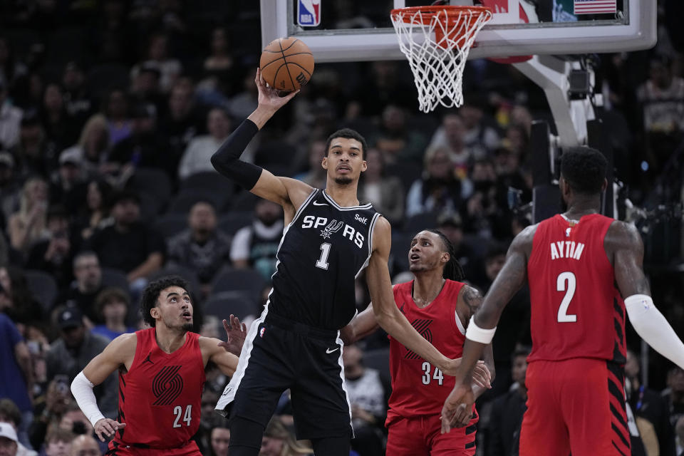 San Antonio Spurs center Victor Wembanyama (1) passes the ball away from Portland Trail Blazers forward Justin Minaya (24) and forward Jabari Walker (34) during the first half of an NBA basketball game in San Antonio, Friday, Jan. 26, 2024. (AP Photo/Eric Gay)