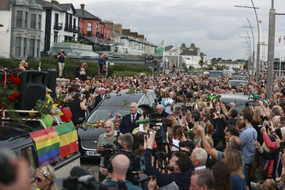 Fans of Sinead O'Connor line the street as her funeral cortege passes through her former hometown of Bray, Co Wicklow, Ireland, Tuesday, Aug. 8, 2023. O’Connor’s family invited the public to line the waterfront in Bray on Tuesday as her funeral procession passes by. Fans left handwritten notes outside her former home, thanking her for sharing her voice and her music. (Liam McBurney/ PA via AP)