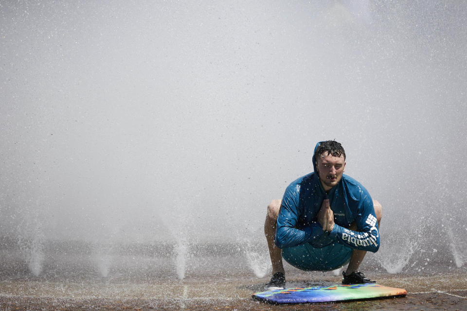 Jesse Moore cools off in the Salmon Street Springs fountain in Portland, Ore., Tuesday, July 26, 2022. Temperatures are expected to top 100 degrees F (37.8 C) on Tuesday and wide swaths of western Oregon and Washington are predicted to be well above historic averages throughout the week. (AP Photo/Craig Mitchelldyer)